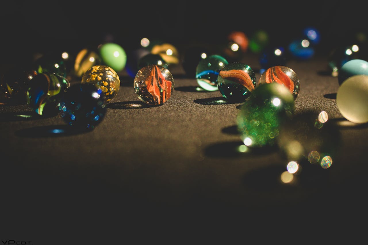 A vibrant collection of glass marbles glistening on a dark surface, showcasing rich colors and textures.